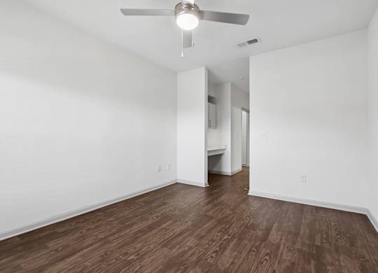 A room with a ceiling fan and wooden flooring.