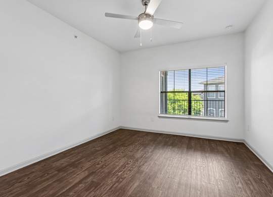 Empty room with a window and a ceiling fan.