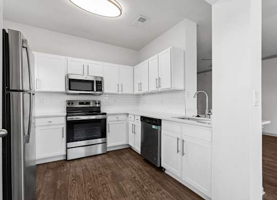 A kitchen with white cabinets and appliances.