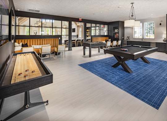 A pool table is in the middle of a room with a blue rug at Folksong Apartments, Georgia 30542