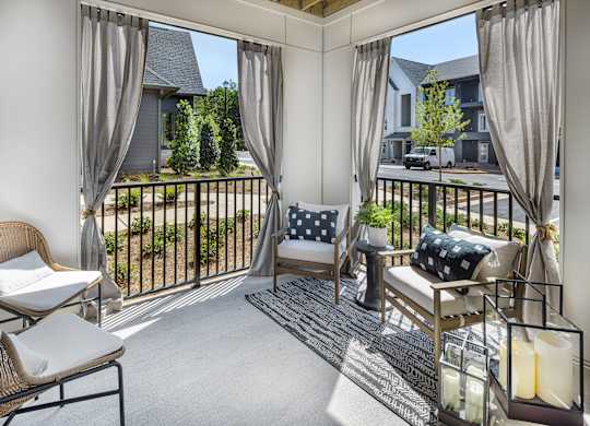 A sunny balcony with a chair, cushion and table at Folksong Apartments, Georgia