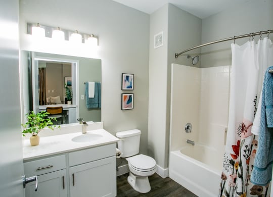 Octave Apartments  a bathroom with a white sink and toilet next to a white bathtub with a shower curtain at Octave Apartments, Las Vegas, Nevada