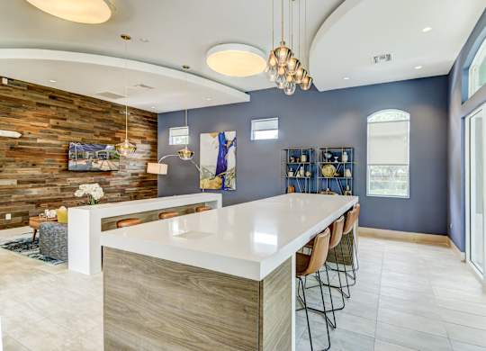 Community lounge room with a large stone table with barstools at Tuscany Bay Apartments, Tampa