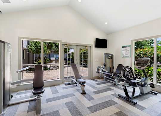 A gym with a variety of equipment including treadmills, weights, and exercise machines.