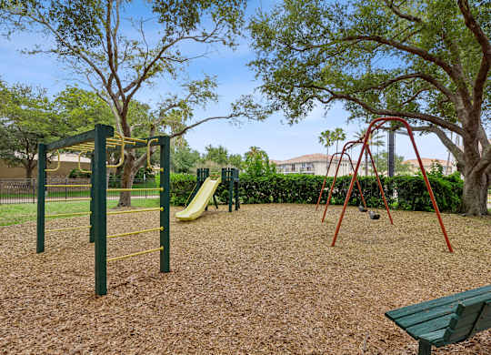 A playground with a yellow slide, green swings, and a green bench.