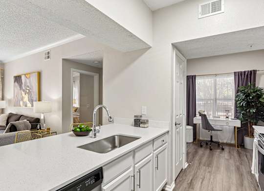 A modern kitchen with a white countertop and stainless steel appliances.