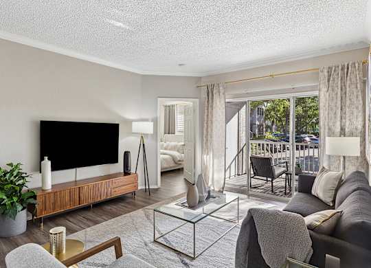 A modern living room with a flat screen TV and a glass coffee table.