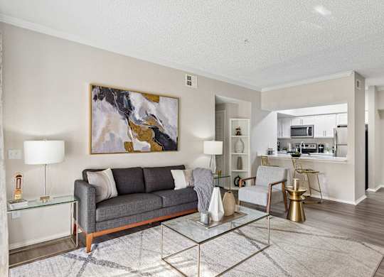 A modern living room with a grey sofa and a glass coffee table.