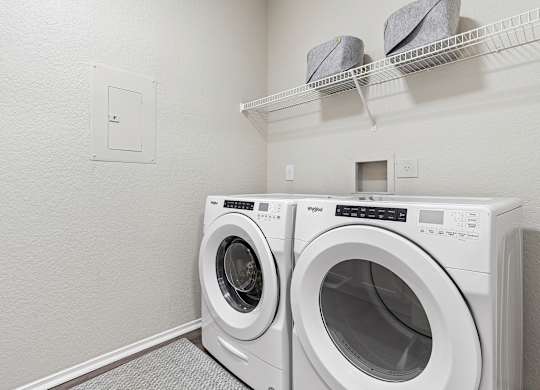 Two white front load washing machines in a laundry room.