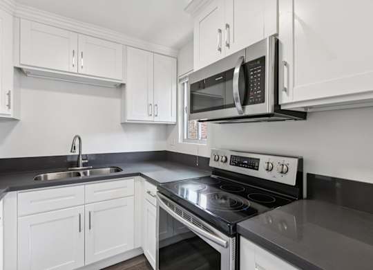 A modern kitchen with white cabinets and a black countertop.