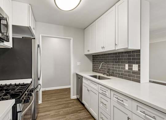 A kitchen with white cabinets and a black stove top.