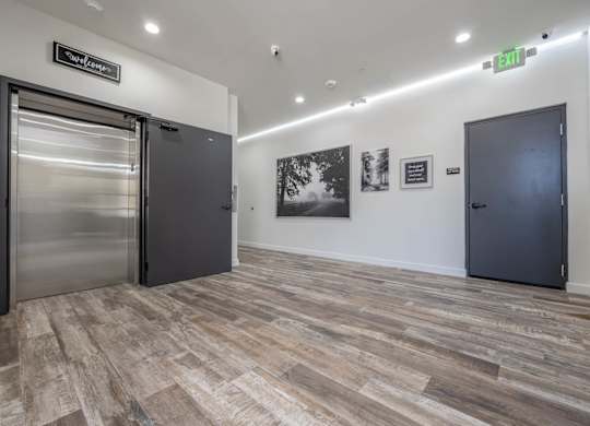 A hallway with a green exit sign and a stainless steel door on the left.
