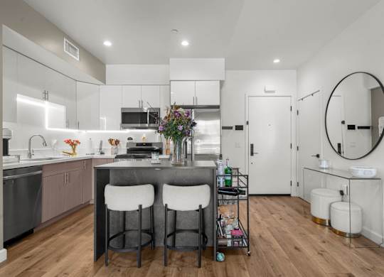 A modern kitchen with a bar stool and a round mirror.