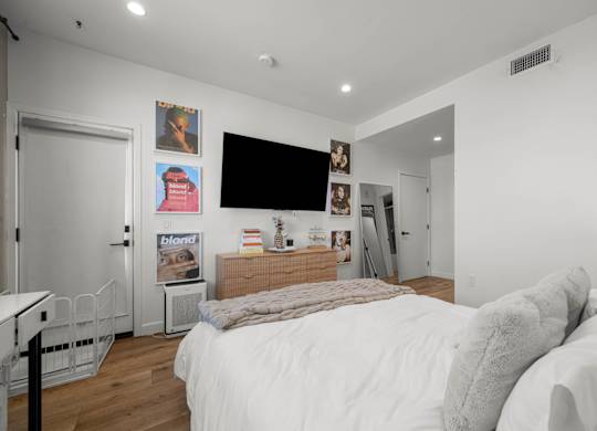 A bedroom with a large bed and a flat screen TV mounted on the wall.