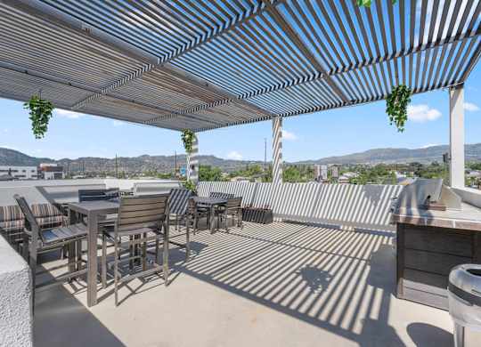 A patio with a striped awning and a table and chairs.