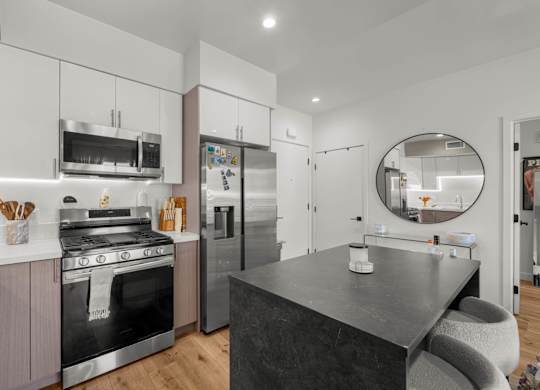 A modern kitchen with a black countertop and stainless steel appliances.
