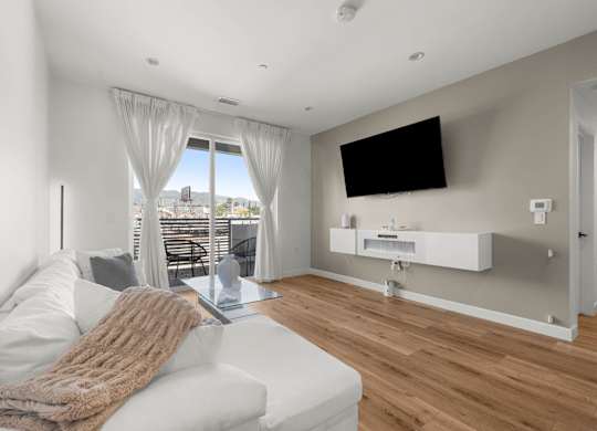 A modern living room with a white couch and a flat screen TV mounted on the wall.