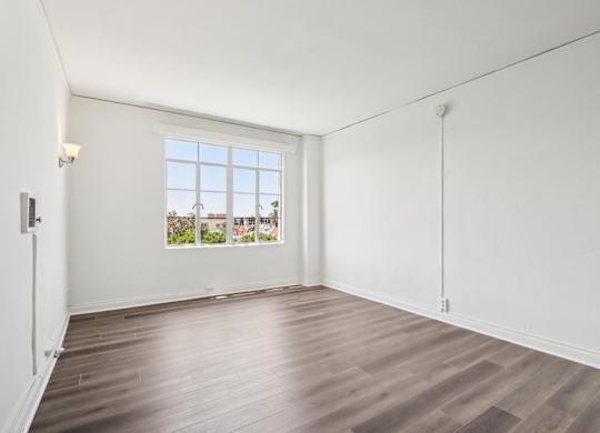 A room with a window and wooden flooring.