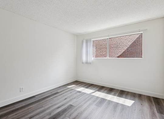A room with a window and wooden flooring.