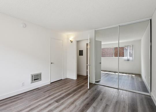 A room with a white wall and a mirror on the door.