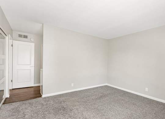 A room with a carpeted floor and a white door.