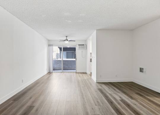A room with a ceiling fan and sliding glass doors.