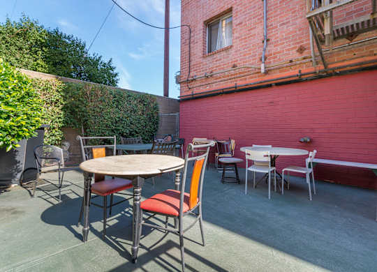 A patio with a table and chairs is surrounded by a red wall.