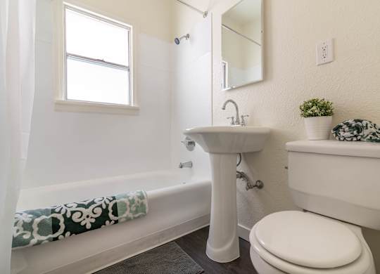 A white bathroom with a toilet, sink, and bathtub.