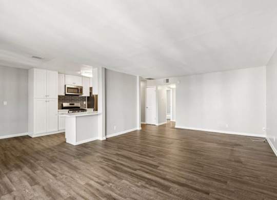 A spacious room with wooden flooring and white walls.