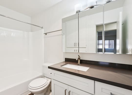 A white bathroom with a toilet, sink, and mirror.