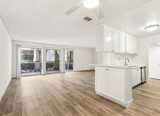A kitchen with white cabinets and a wooden floor.