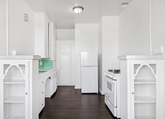 A white kitchen with a wood floor and white appliances.