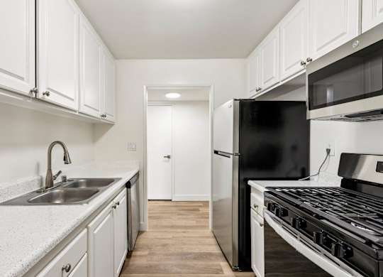 A kitchen with black appliances and white cabinets.