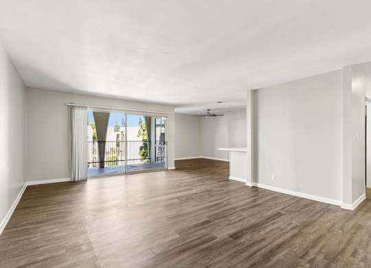 A spacious room with wooden flooring and white walls.