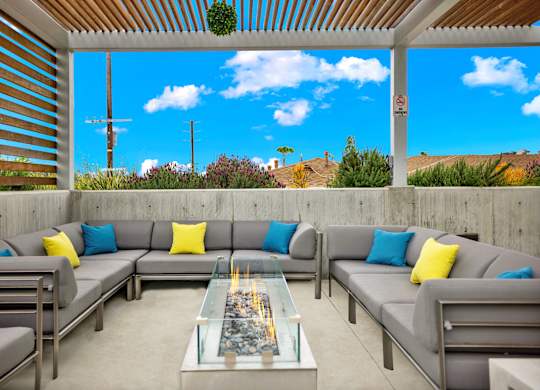A patio with grey couches and a glass table.