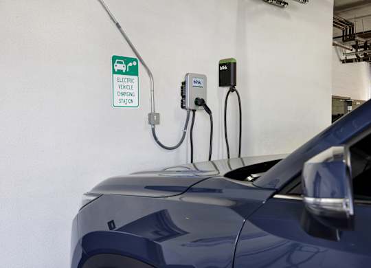 A blue car is plugged into an electric vehicle charging station.