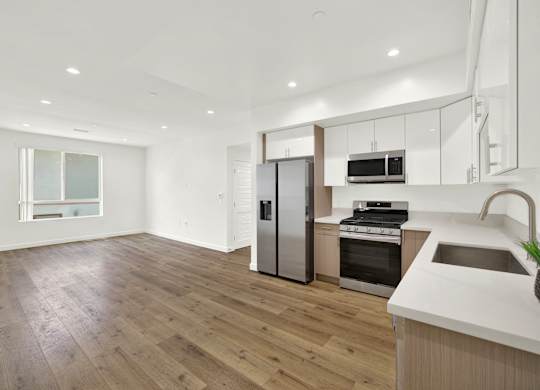 A modern kitchen with wooden floors and stainless steel appliances.