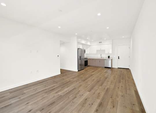 A spacious room with wooden flooring and white walls.