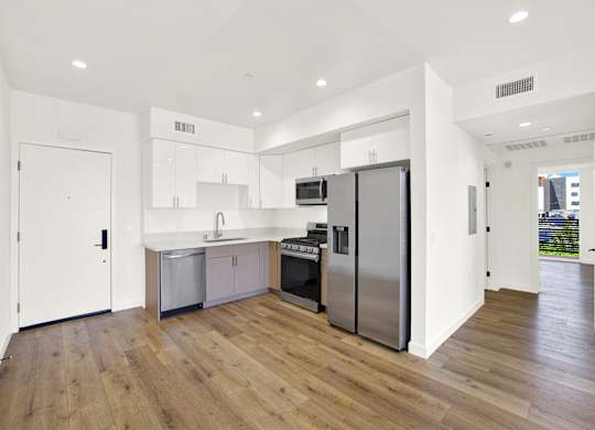 A modern kitchen with wooden floors and stainless steel appliances.