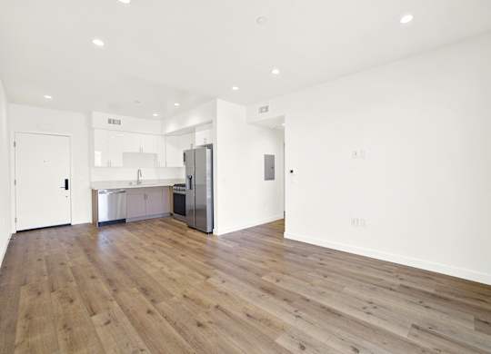 A kitchen with a refrigerator, sink, and cabinets is visible.