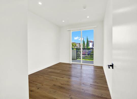 A room with a wooden floor and a sliding glass door.