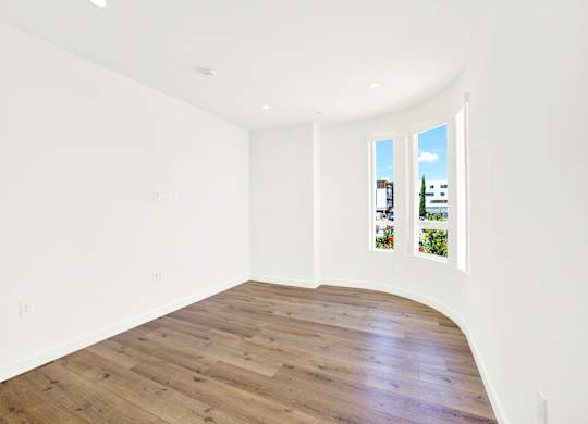 A room with wooden flooring and white walls.
