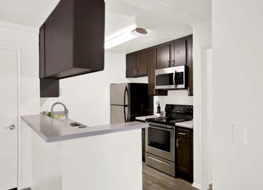 A kitchen with a white counter top and stainless steel appliances at Monterra Ridge Apartments, Canyon Country