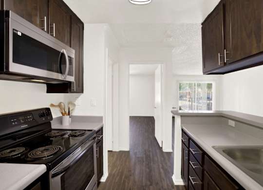 A kitchen with dark wood cabinets and stainless steel at Monterra Ridge Apartments, Canyon Countryappliances.