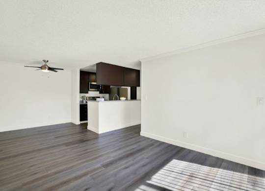 A room with a ceiling fan and a kitchen area at Monterra Ridge Apartments, Canyon Country, California