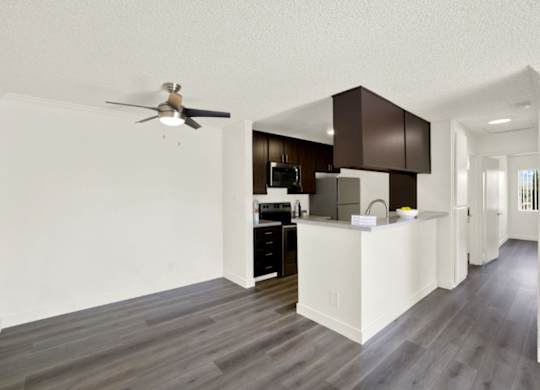 A modern kitchen with dark wood cabinets and a white island at Monterra Ridge Apartments, Canyon Country, 91351