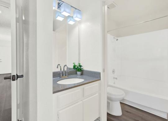 A white bathroom with a sink, toilet, and bathtub at Monterra Ridge Apartments, Canyon Country