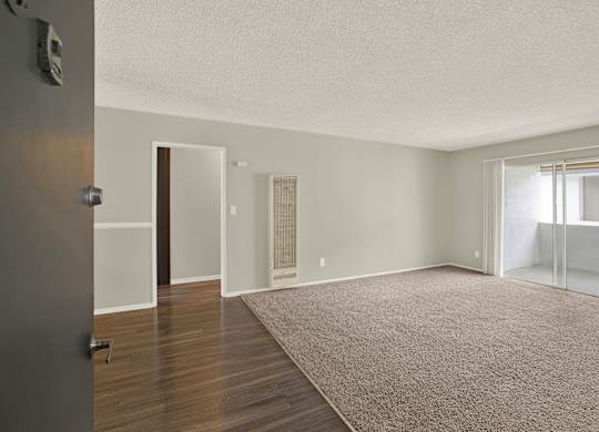 A room with a carpeted floor and a door on the left at The Square in Downey, CA, 90242