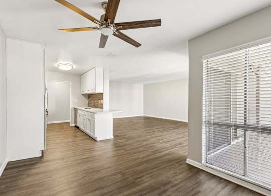 A room with a ceiling fan and wooden flooring.
