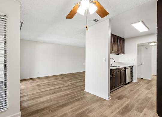 A kitchen area with wooden flooring and a white wall.